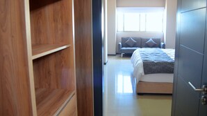 Un dormitorio con una cama, un sofá gris y un armario de madera.