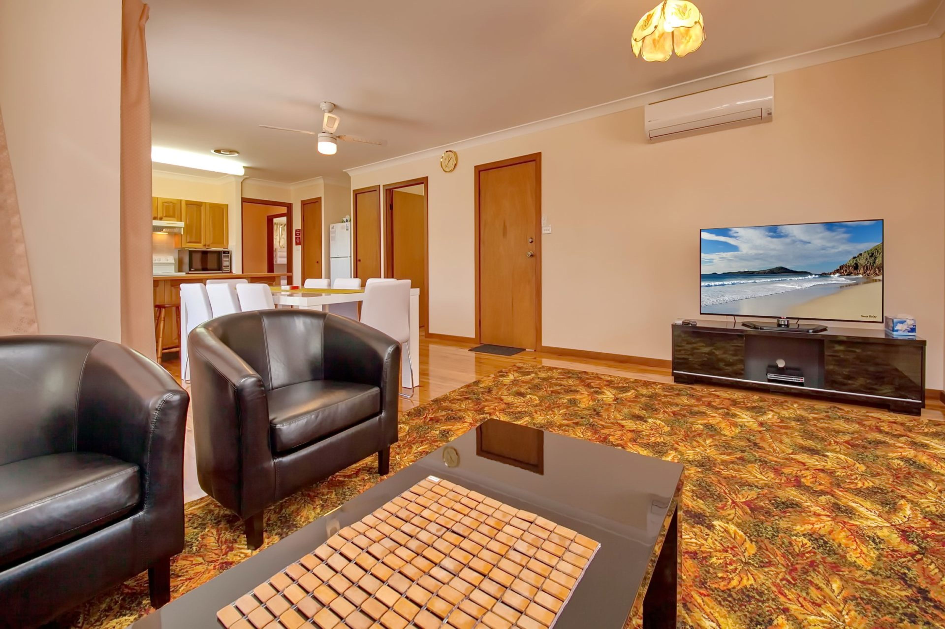 A living room with a sofa, a coffee table, a television, and a patterned carpet.