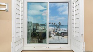 A window with a view of a beach, palm trees, and a pier. - Pier View Escape (Oceanside)