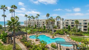 A resort with a large pool, palm trees, and a view of the ocean. - Pier View Escape (Oceanside)