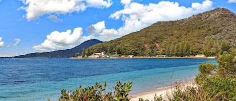 A coastal landscape with a clear sky, a mountain in the background, and a body of water in the foreground.