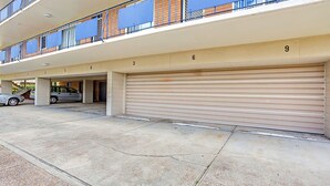 Un estacionamiento de varios niveles con puertas de garaje numeradas, una pasarela techada y un edificio con fachada de ladrillo.