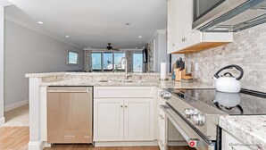 Una cocina moderna con una isla central, electrodomésticos de acero inoxidable y vistas al exterior.