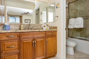A bathroom with a wooden vanity, a large mirror, a shower with glass doors, and a toilet.