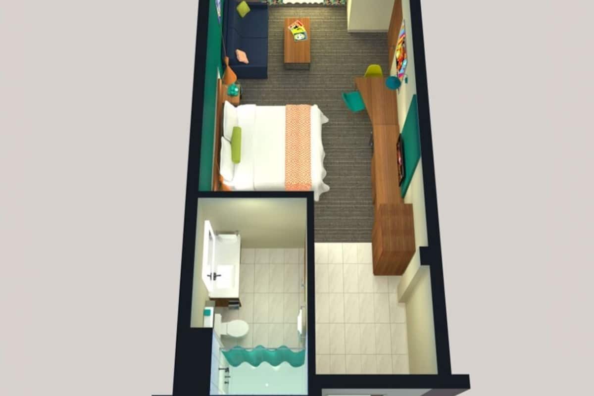 Distribución de una habitación de hotel con cama, escritorio, silla, mesita, sofá, ventana con cortinas y baño con lavamanos e inodoro.