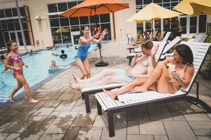 Un área junto a la piscina con sillones de descanso y sombrillas.