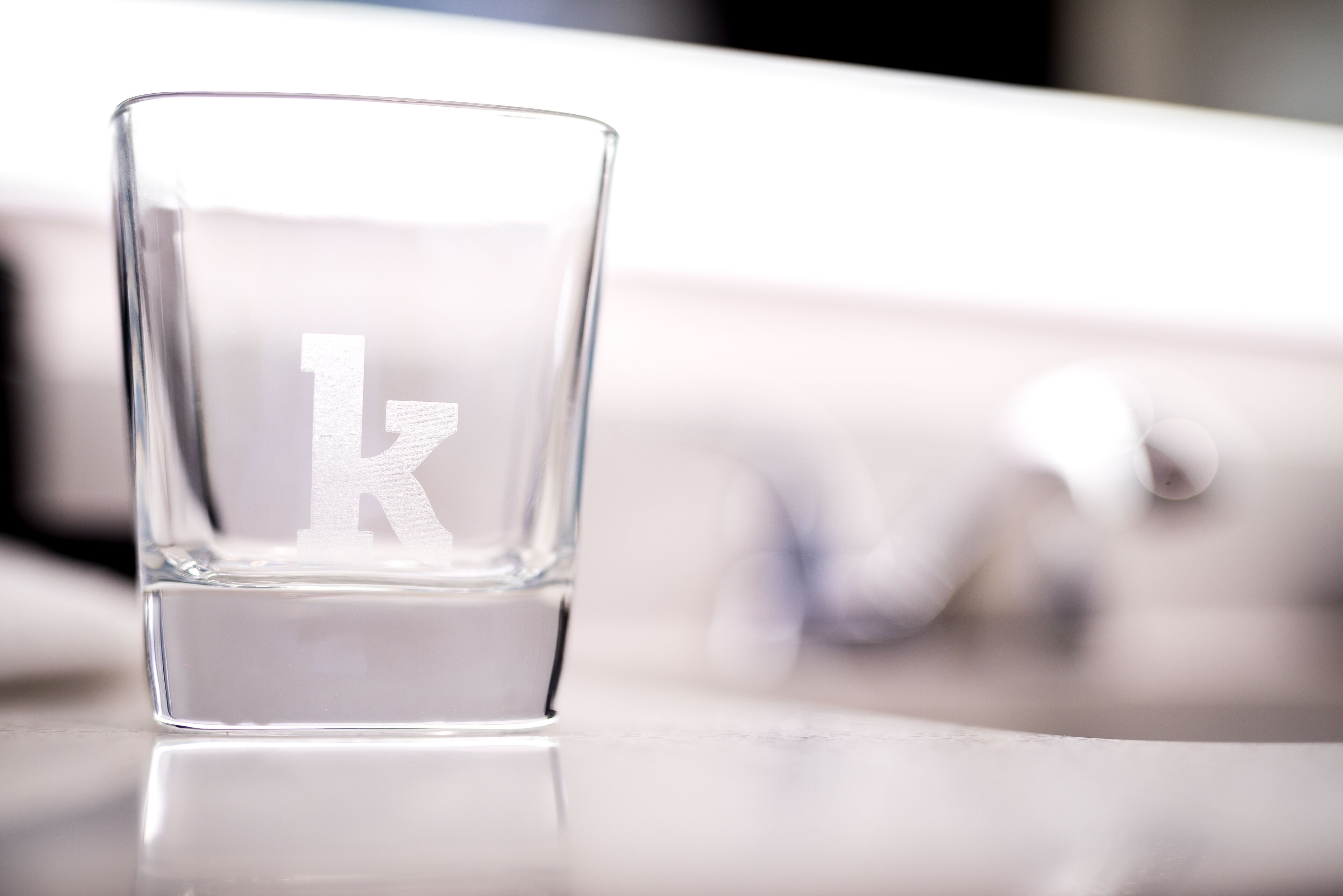 Et gennemsigtigt glas med bogstavet "k" på en reflekterende overflade.