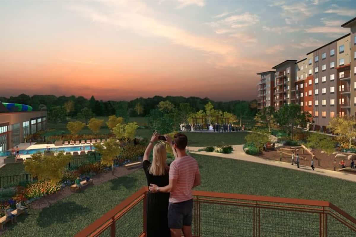Un moderno complejo de apartamentos con piscina, mobiliario exterior y vistas al atardecer.