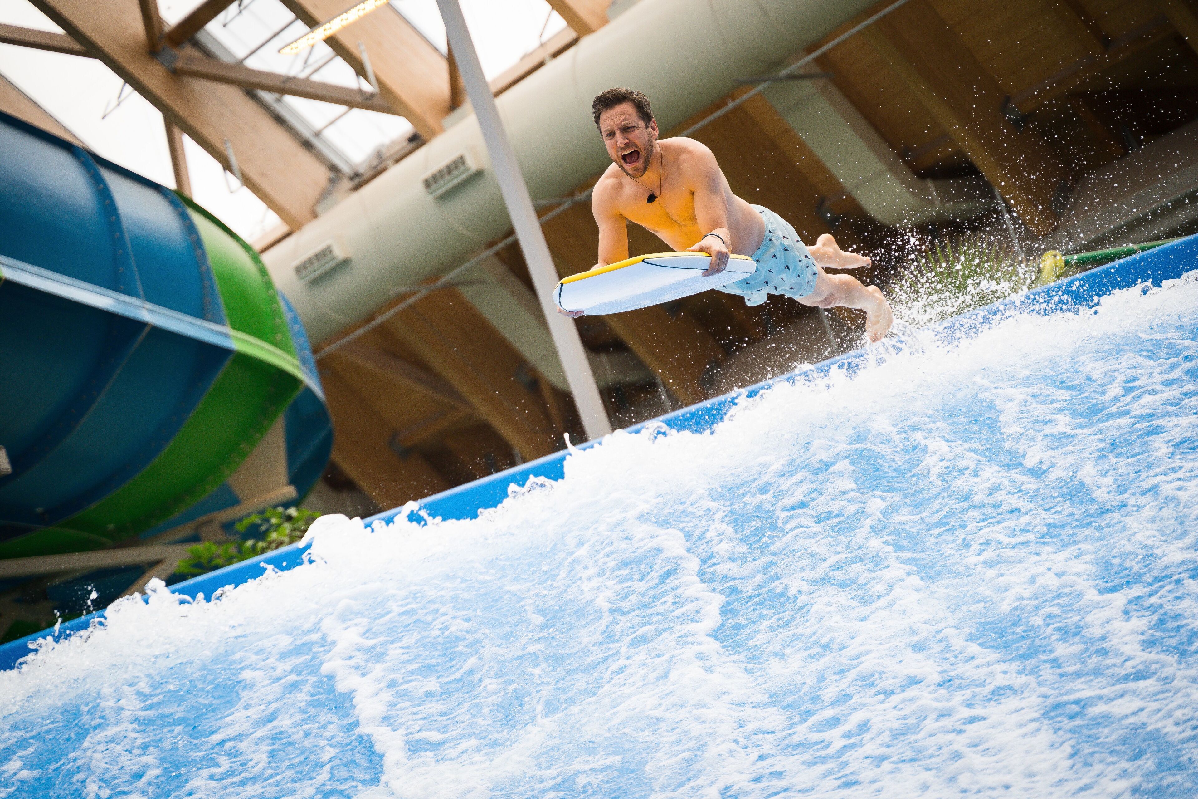 Eine Person surft auf einer Welle in einem Indoor-Wasserpark.