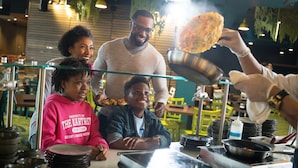 Un restaurant avec un comptoir, une balance numérique et une personne qui sert les plats.
