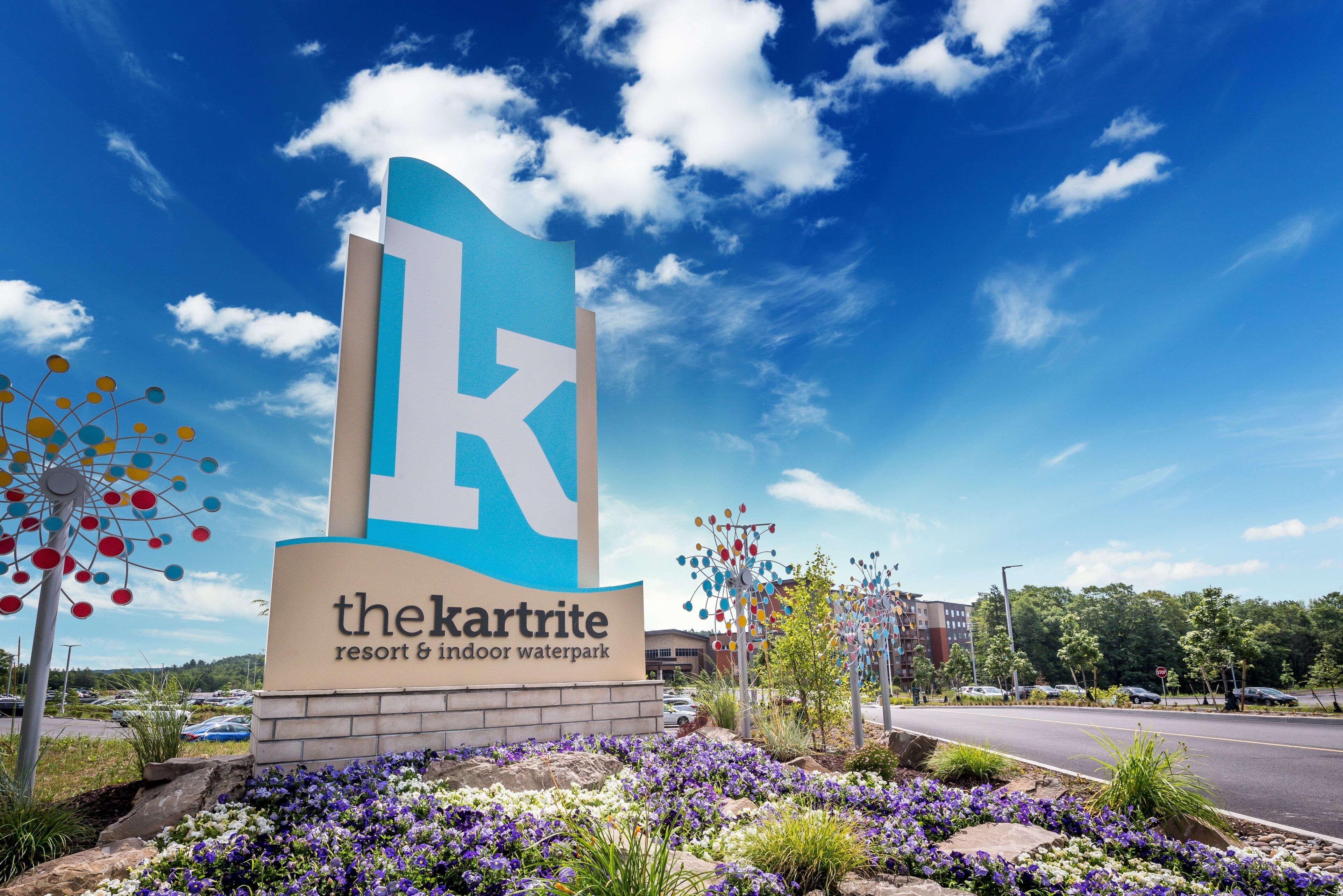 Een bordje voor 'the karrite resort & indoor waterpark' met een heldere lucht en decoratieve bomen.