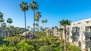 A resort with multiple-story buildings, palm trees, and a well-maintained garden. - Pacific Palms (Oceanside)