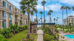A resort with a pool, palm trees, and a view of the ocean. - Pacific Palms (Oceanside)