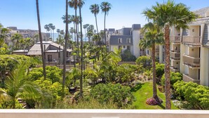 A hotel with multiple floors, a well-maintained garden with palm trees, and a view of the ocean. - Pacific Palms (Oceanside)