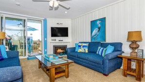 Una sala de estar con un sofá azul, una mesa de centro, una chimenea y un televisor.