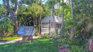 Letrero de North Coast Village, con una estructura de madera al fondo.