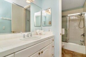A bathroom with a sink, mirror, and shower. - Paradise Found (Oceanside)