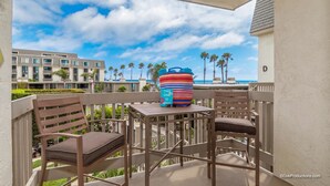 A balcony with two wooden chairs and a striped vase on a small table. - Ocean Breeze Retreat (Oceanside)