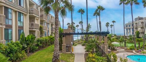 A resort with a pool, palm trees, and a view of the ocean.