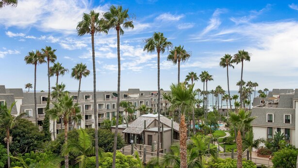 A resort with multiple-story buildings, palm trees, and a pool area. - North Coast Village G-306 Blue Horizons (Oceanside)