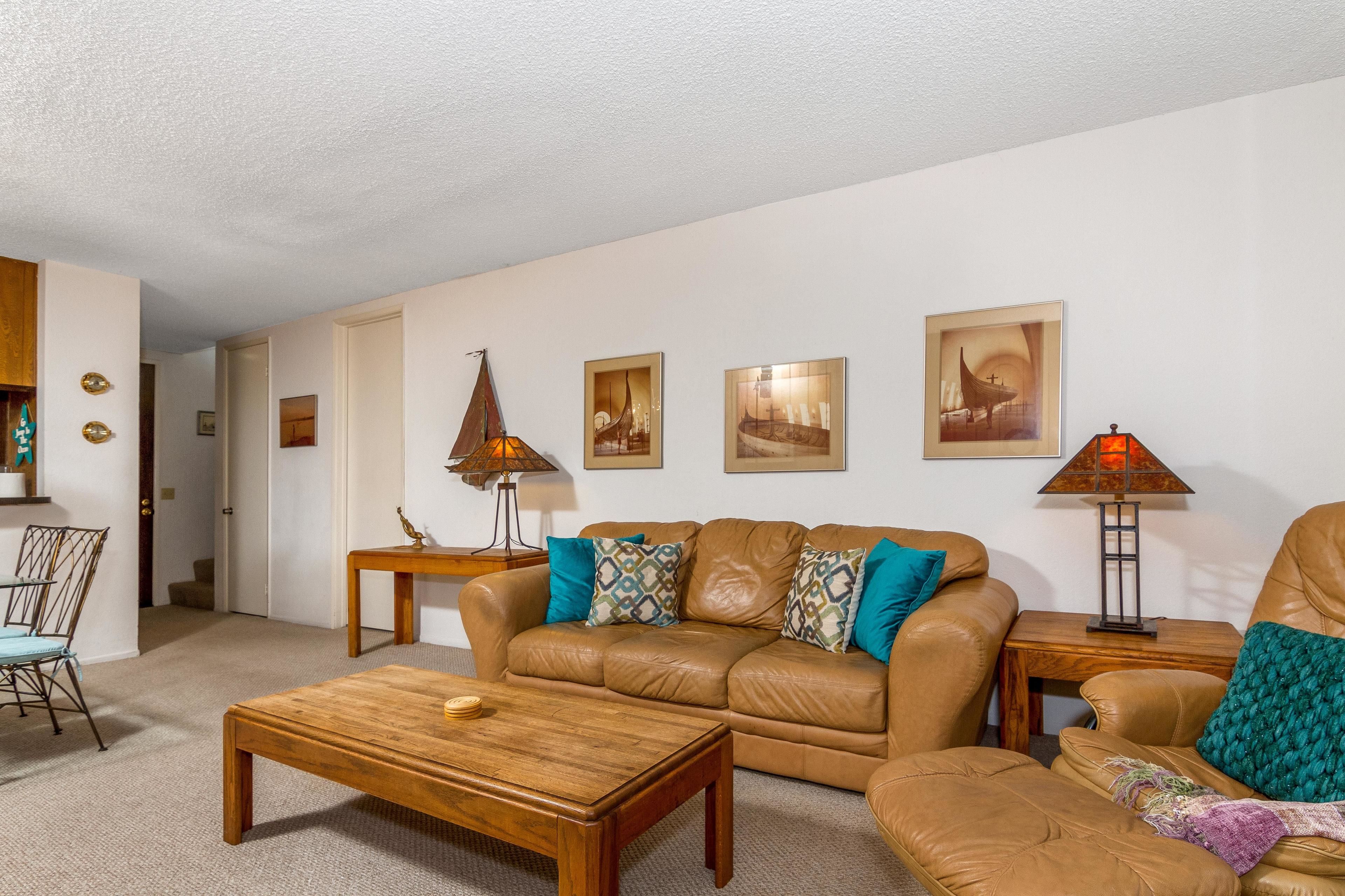A living room with a leather sofa, wooden coffee table, and a dining area with a chair and table.