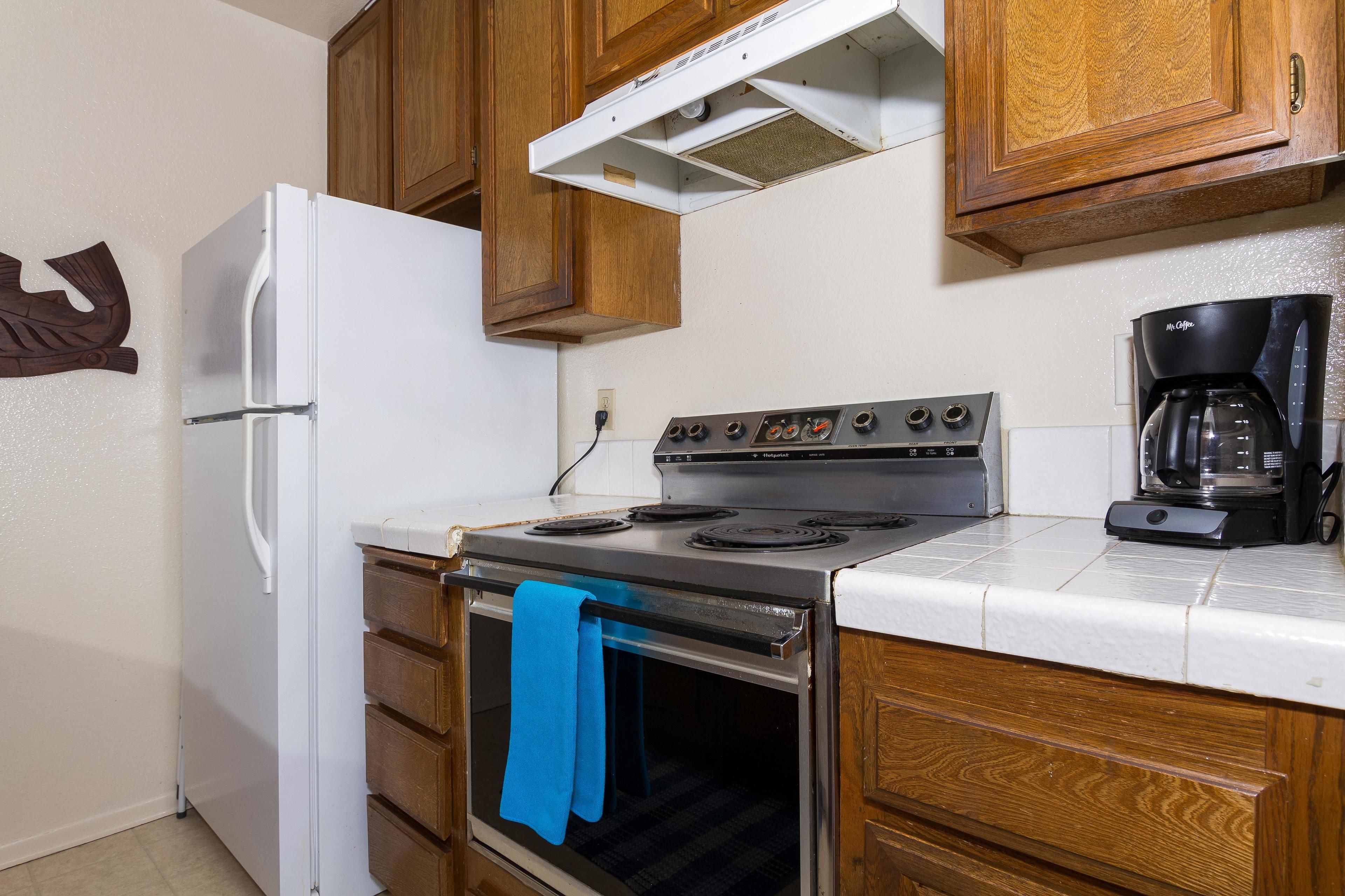 Una cocina con armarios de madera, un refrigerador blanco, una estufa y una cafetera.