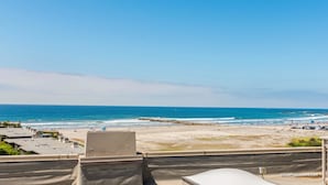 A beach view from a balcony with a clear sky. - Surf View Penthouse (Oceanside)