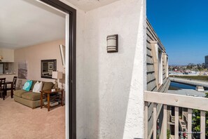Uma varanda com vista para um canal e edifícios, uma sala de estar com sofá, luminária e um quadro na parede.