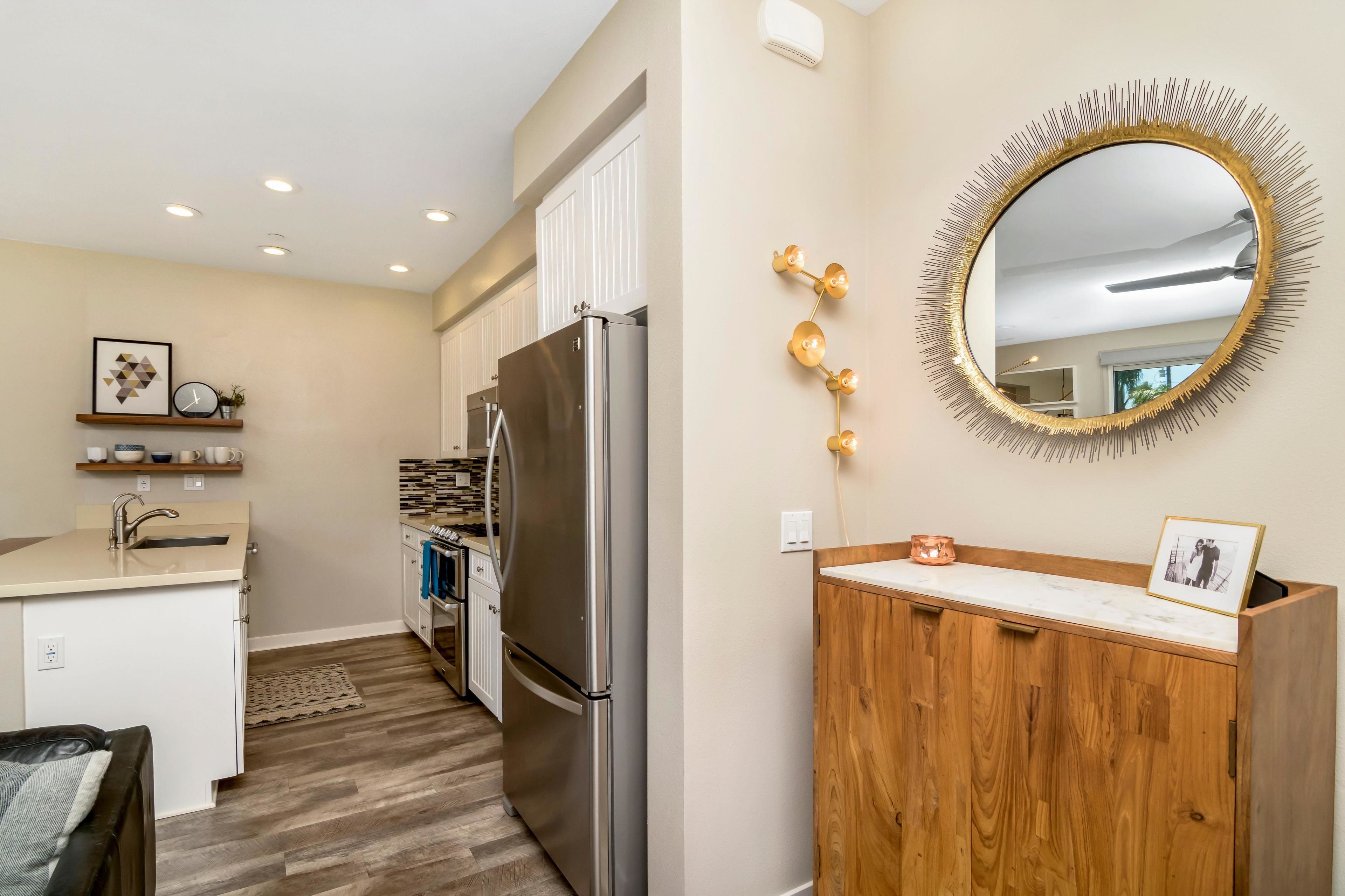 A modern kitchen with a stainless steel refrigerator, wooden cabinets, and a marble countertop.