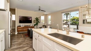 Una cocina moderna con una isla grande, armarios blancos, horno empotrado y ventilador de techo.