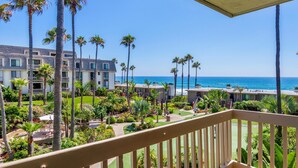 Een hotel met een balkon met uitzicht op een strand en de oceaan.