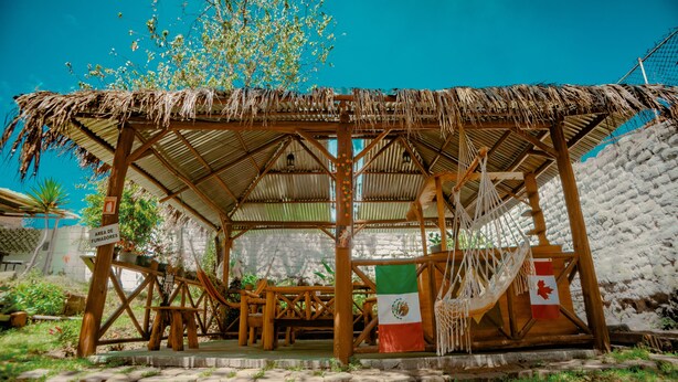 Una estructura de madera con techo de paja, una bandera y un letrero que indica una zona para fumadores.