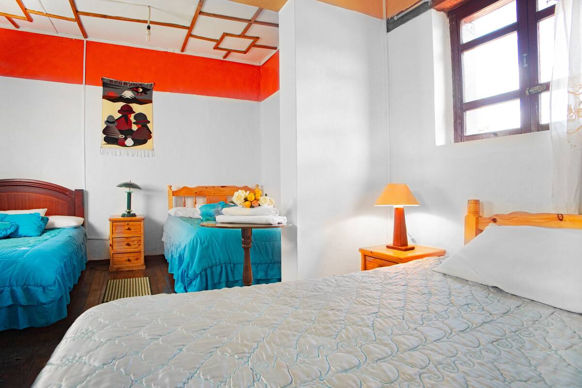 A bedroom with two beds, a wooden headboard, a nightstand, a lamp, and a poster on the wall.