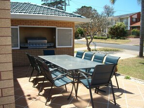 Eine Außenpatio mit Grillplatz aus Ziegelsteinen, einem Tisch und Stühlen.