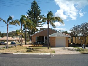 A residential house with a garage, surrounded by palm trees and a clear sky.