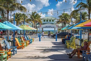 A beachside seating area with colorful chairs and umbrellas, a clear sky, and a building with a sign reading 'LAURENDAL BY THE SEA'. - Ocean Reef Hotel (Fort Lauderdale)
