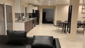 A modern living room with a sectional sofa, a dining area with a table and chairs, and a kitchen with a refrigerator and microwave. - Newly Renovated 5 Bedroom Home with Gorgeous Views just minutes from Slopes (Hunter)
