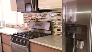 A modern kitchen with stainless steel appliances, a tiled backsplash, and wooden cabinetry. - Newly Renovated 5 Bedroom Home with Gorgeous Views just minutes from Slopes (Hunter)