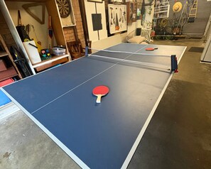 A ping pong table with a red paddle in the foreground.