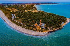 Vista aérea de una zona costera con un faro, playa y edificios residenciales.