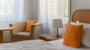 Ein Hotelzimmer mit einem Bett, einem Sessel, einem Tisch und einer Lampe.