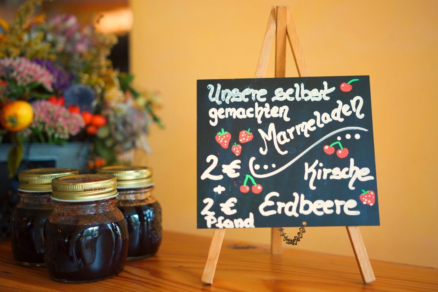 A chalkboard sign listing prices for homemade jams and preserves.