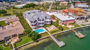 An aerial view of a waterfront property with a large house, a swimming pool, and a dock. - Amadeus 2 Top location, water font, steps to beach, restaurants and shopping! (Treasure Island)