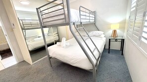 A bunk bed room with a small bedside table and a lamp.