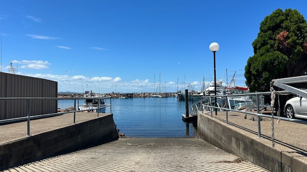 Un port de plaisance avec des bateaux amarrés, une promenade en béton menant à l’eau et un lampadaire.