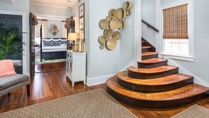 A staircase with wooden steps leading to a second floor, a wall with woven baskets, and a room with a bed and a desk.