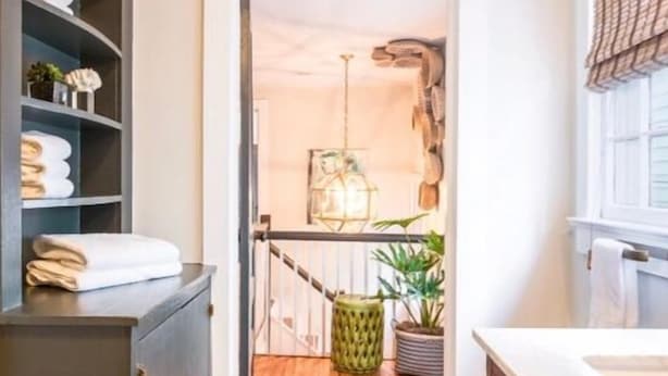 A narrow hallway with a wooden floor leading to a room with a hanging light fixture and a plant. - 69B Spring Street - 2 BR / 1 BA Holiday home 2 (Charleston)