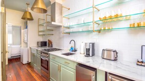 Una cocina moderna con encimera de mármol, electrodomésticos de acero inoxidable y estanterías de vidrio.