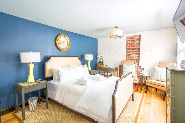 A hotel room with a bed, bedside tables, a desk, a chair, and a TV.