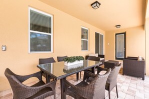 An outdoor patio with a glass-top table surrounded by wicker chairs, a small sofa, and a potted plant. - Encore Resort at Reunion - 641 Lasso Drive (Kissimmee)